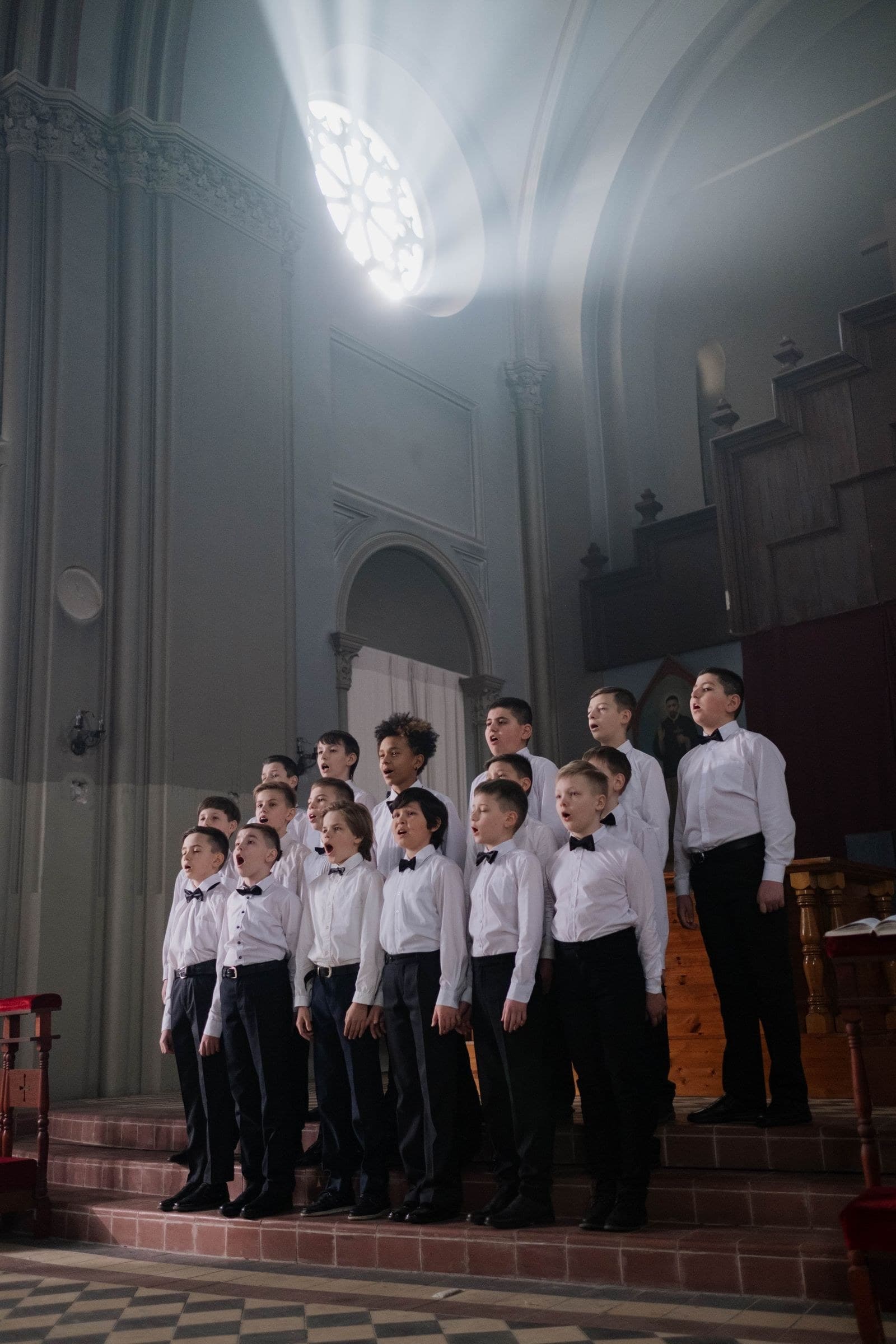 Chorale d'enfants en aube blanche chantant dans une église